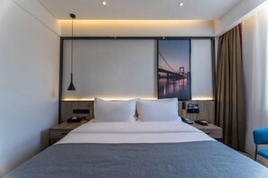 A modern hotel room with a large bed, bedside tables, a desk, and a chair.