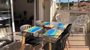 A glass-top dining table with chairs, a refrigerator, and a view of the surrounding area. - Spacious & comfortable T2 air-conditioned 3* Wifi, Private parking, Beach 100m (Saint-Mandrier-sur-Mer)