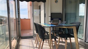 A balcony with a glass door, a table with chairs, and a small grill. - Spacious & comfortable T2 air-conditioned 3* Wifi, Private parking, Beach 100m (Saint-Mandrier-sur-Mer)