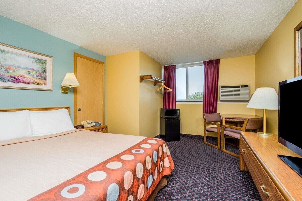 Une chambre d’hôtel équipée d’un lit, d’un bureau, d’une chaise, d’une télévision et d’une fenêtre avec des rideaux.