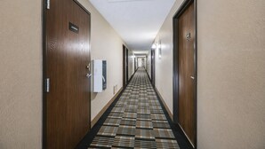 A hotel hallway with wooden doors, a patterned carpet, and a ceiling light fixture. - Hotel 8 (Fergus Falls)