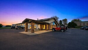 A motel with a brick facade, a covered outdoor seating area, and a parking lot. - Hotel 8 (Fergus Falls)