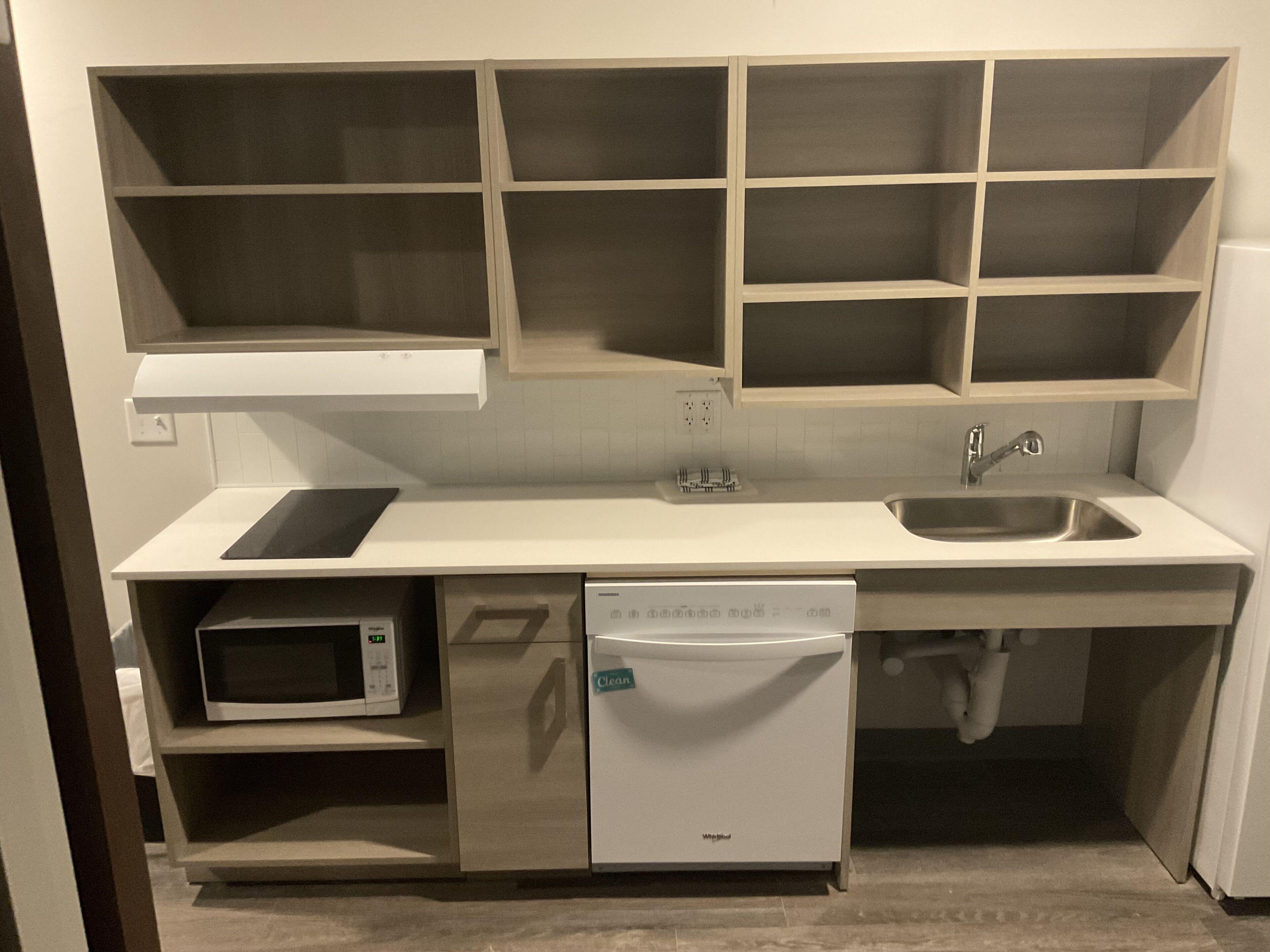 Una cocina compacta equipada con microondas, lavavajillas y un fregadero.