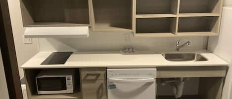 Una cocina compacta equipada con microondas, lavavajillas y un fregadero.