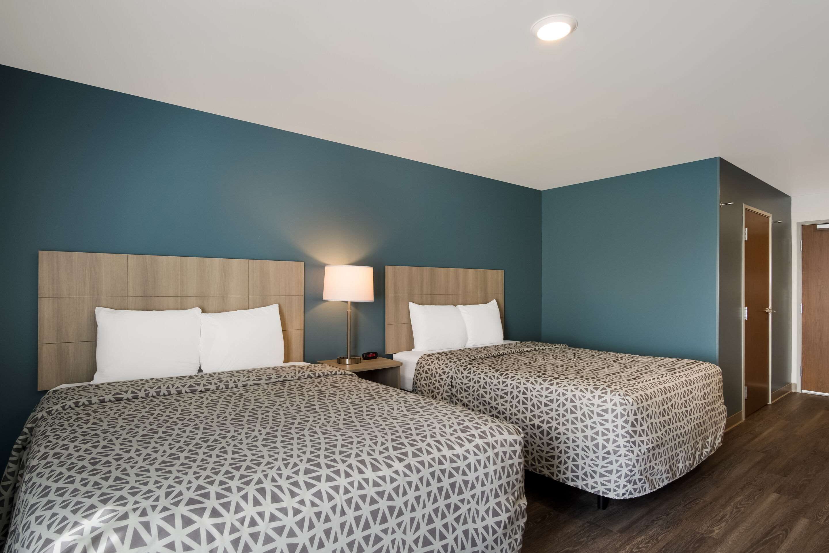 A hotel room with two beds, a nightstand, and a door.