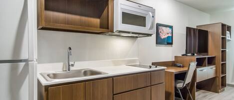 Una cocina compacta con microondas integrado, un lavabo y armarios de madera.