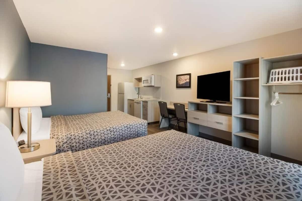 Une chambre d’hôtel avec deux lits, un bureau, une télévision et une armoire.