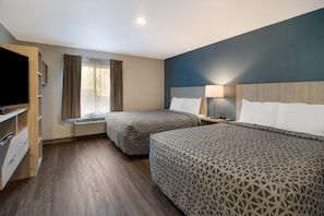 Une chambre d’hôtel avec deux lits, une télévision, un radiateur et une fenêtre avec des rideaux.