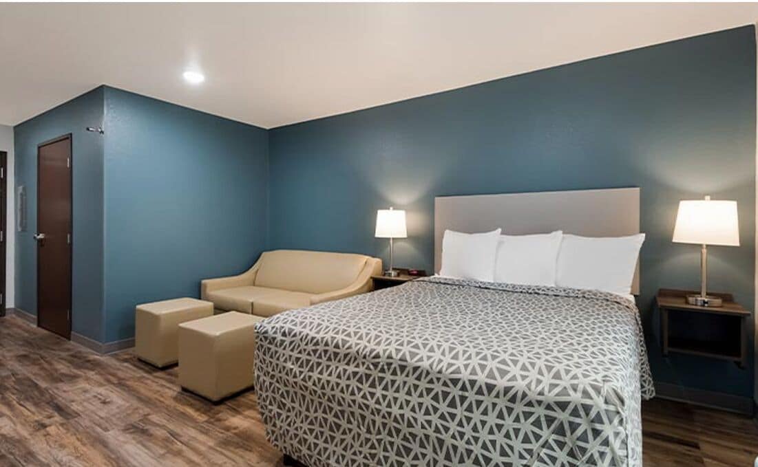 Une chambre d’hôtel comprenant un lit, un canapé, deux tables de chevet avec des lampes et une porte.
