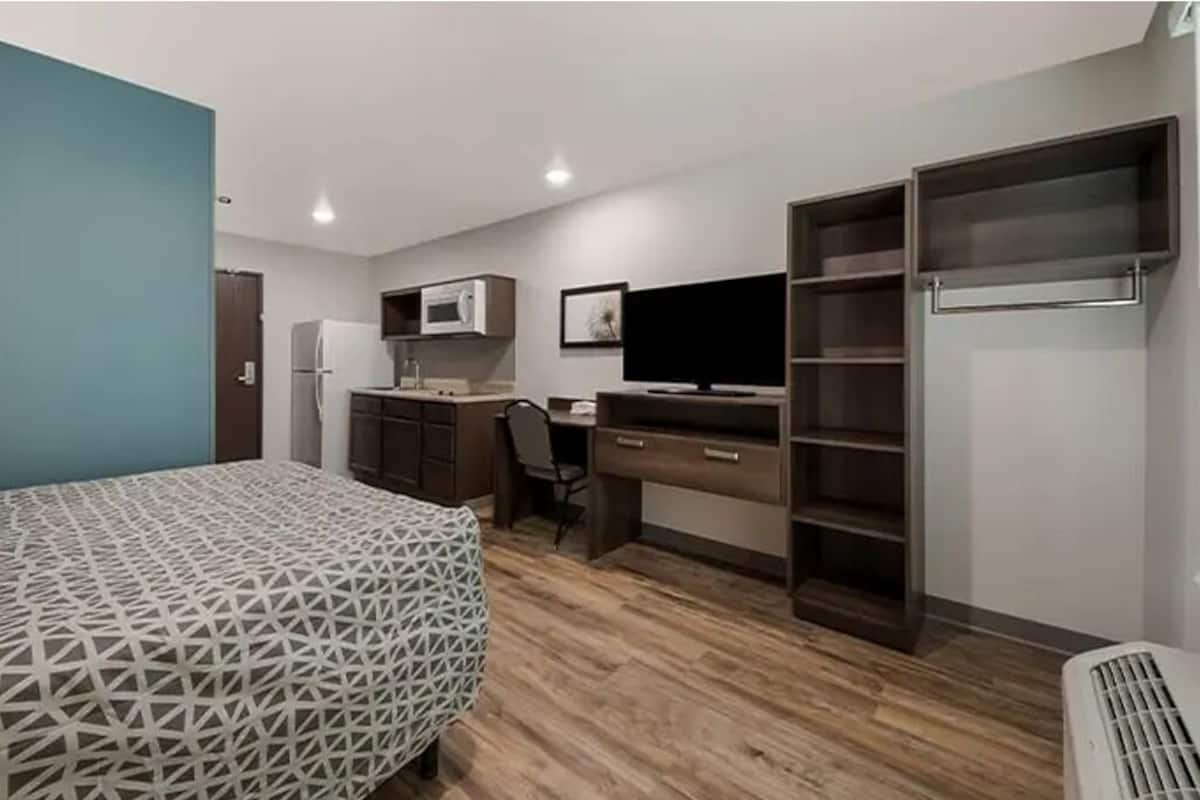 Une chambre comprenant un lit, un bureau, une chaise, une télévision, une armoire et un four à micro-ondes.
