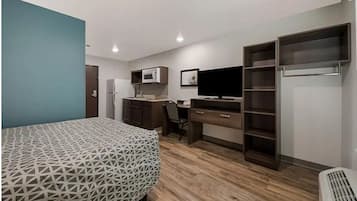 Une chambre comprenant un lit, un bureau, une chaise, une télévision, une armoire et un four à micro-ondes.