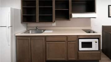 A kitchen with wooden cabinets, a white refrigerator, a sink, and a built-in microwave.