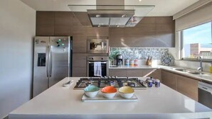 Una cocina moderna con una isla central, electrodomésticos de acero inoxidable y un amplio ventanal que proporciona luz natural.
