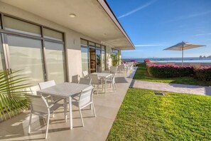 A modern outdoor patio with white furniture, a well-maintained lawn, and a view of the ocean. - Summer Savings!! Ocean view w/private Rooftop villa & 5min /downtown (Cabo San Lucas)
