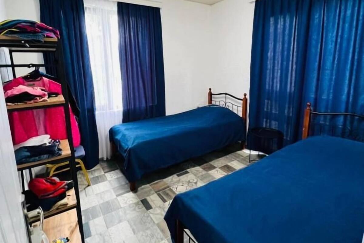 A small, compact room with two single beds, a bunk bed, and a wardrobe.