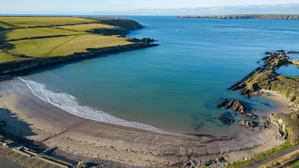 An aerial view of a coastal area with a beach, rocky shoreline, and fields. - The Old Stables - 3 Bedroom Cottage - Angle (Angle)