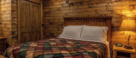 Un dormitorio con paneles de madera en la pared, una cama con colcha colorida, almohadas blancas y una mesita de noche con un reloj.
