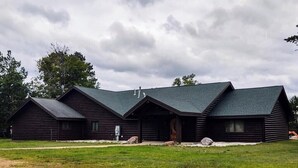 A log cabin with a steeply pitched roof and a central chimney. - Phelps Lakeview Lodge Holiday House (Phelps)