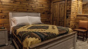 A wooden-paneled room with a bed, a nightstand, and a chair. - Phelps Lakeview Lodge Holiday House (Phelps)
