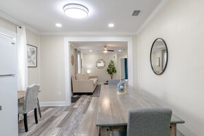 Un coin repas avec une table en bois, des chaises, un canapé et un ventilateur de plafond.