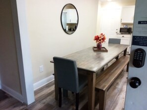 A dining area with a wooden table, chairs, and a vase with flowers. - Modern Home, Great Deck & Yard- Peaceful at Potter (Mobile)