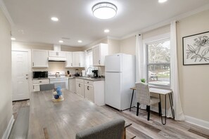 Une cuisine moderne avec des meubles blancs, une table à manger et une fenêtre donnant sur un beau paysage.