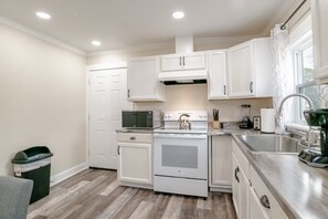 A kitchen with white cabinets, a stove, a microwave, and a sink. - Modern Home, Great Deck & Yard- Peaceful at Potter (Mobile)