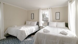 Habitación de hotel con dos camas, un tapete estampado y una ventana con cortinas.