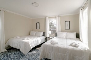Une chambre d’hôtel avec deux lits, un tapis à motifs et une fenêtre avec des rideaux.