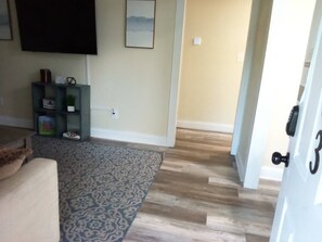 A living room with a patterned rug, a sofa, a TV, and a bookshelf. - Modern Home, Great Deck & Yard- Peaceful at Potter (Mobile)