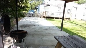 Un patio trasero con una parrilla, una mesa de picnic y una casa al fondo.