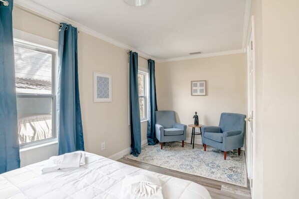 A hotel room with a bed, two armchairs, a small table, and a window with curtains. - Modern Home, Great Deck & Yard- Peaceful at Potter (Mobile)