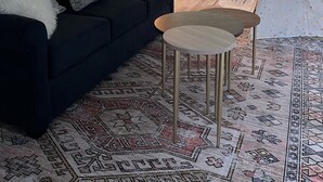 A cozy living room with a dark sofa, patterned pillows, a small round table, and a decorative rug.