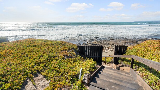 A wooden staircase leading to a beach with a view of the ocean.