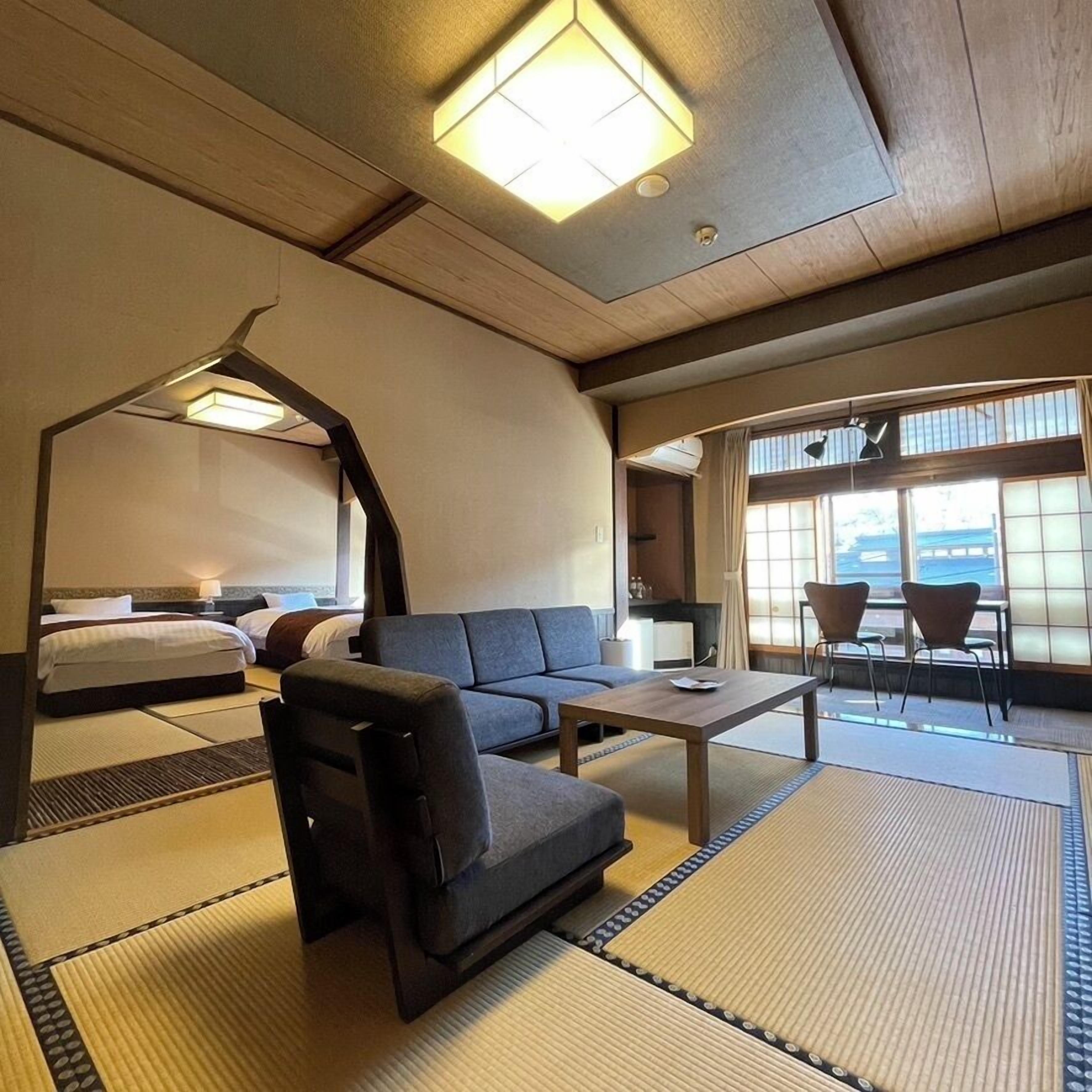 Une chambre d’hôtel avec un canapé, une petite table, un lit et une vue sur l’extérieur grâce à de grandes fenêtres.