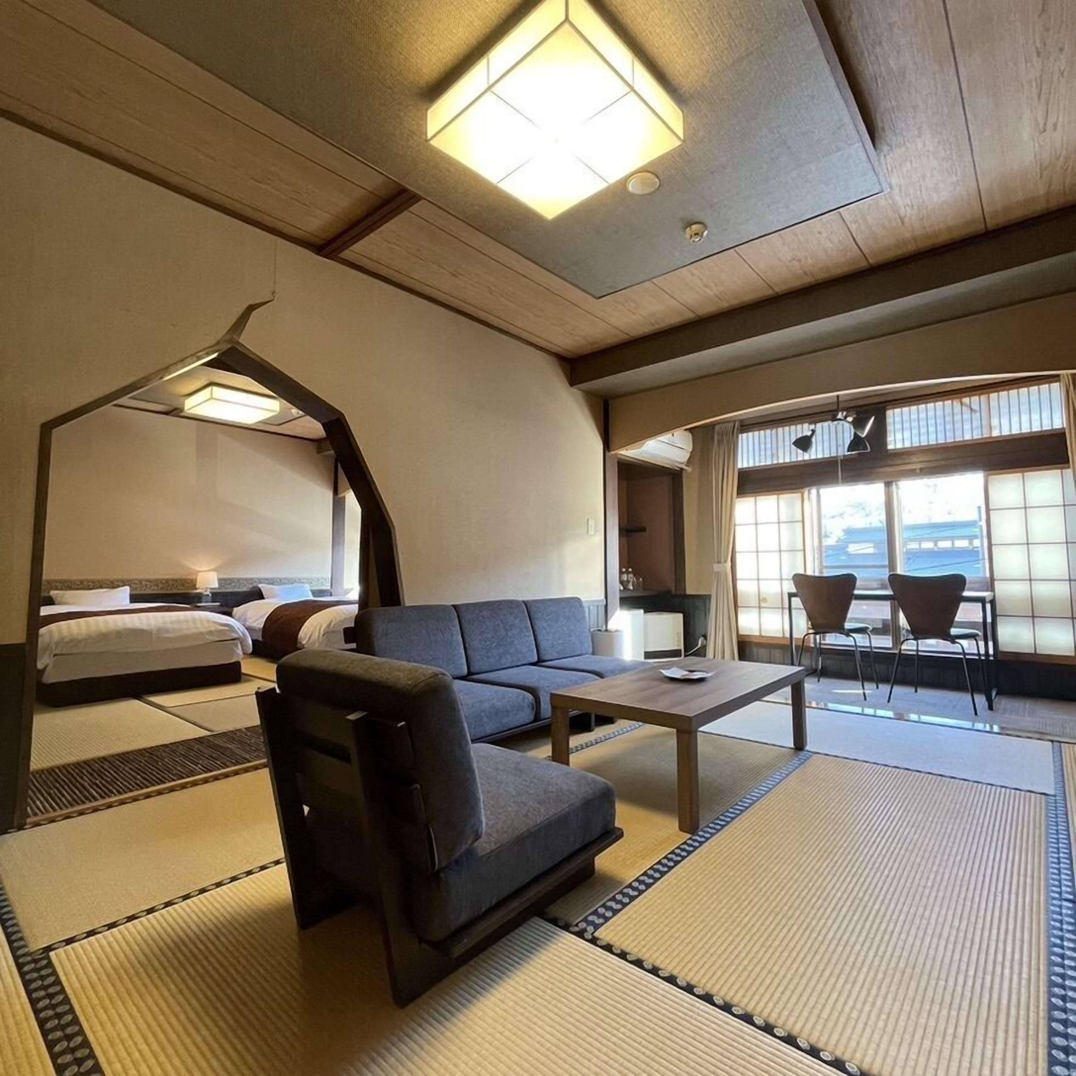Une chambre d’hôtel avec un canapé, une petite table, un lit et une vue sur l’extérieur grâce à de grandes fenêtres.