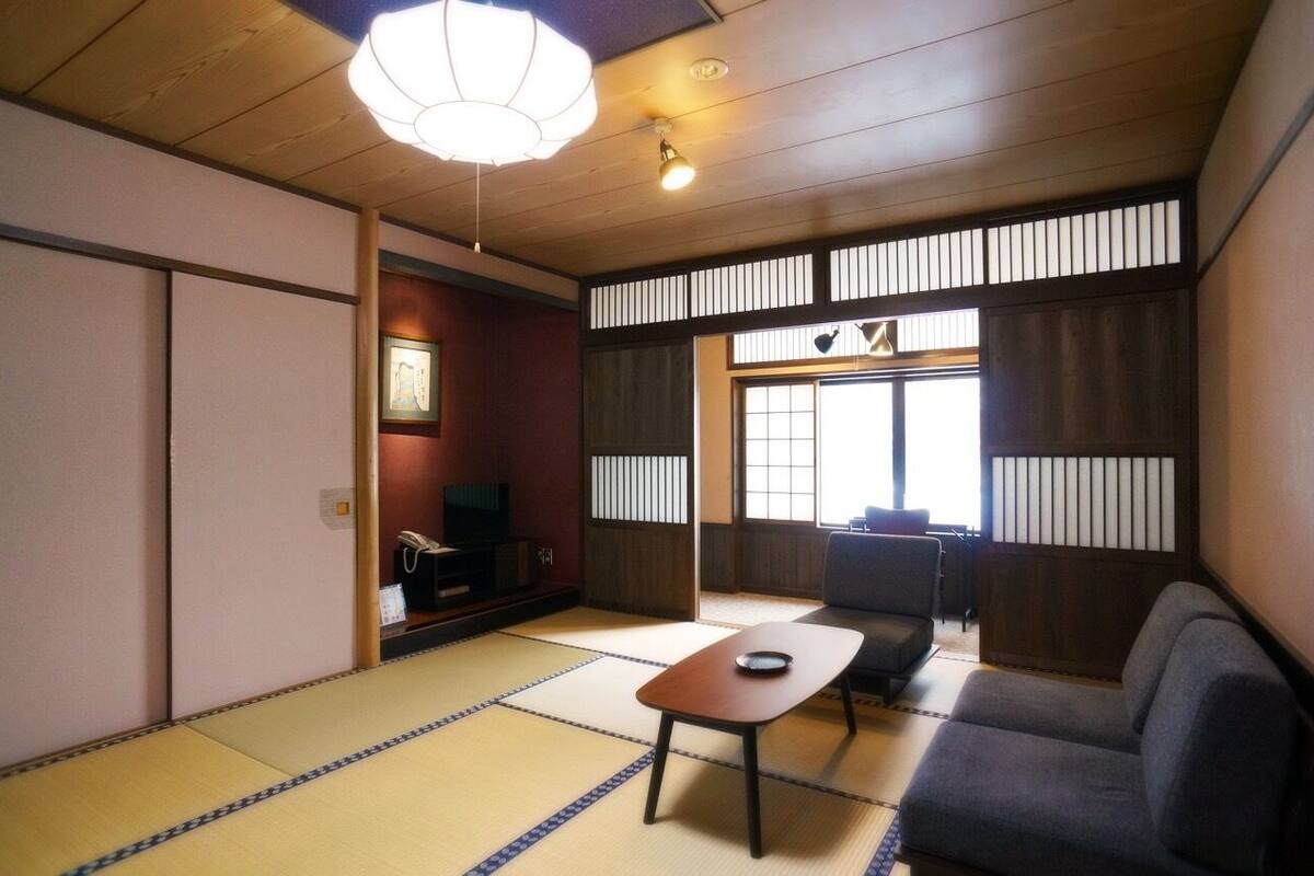 A traditional Japanese room with tatami flooring, a low table, a sofa, and sliding doors.