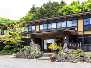 A building with a traditional entrance, a sign with Japanese characters, and a stone pathway leading to the entrance. - Takayu Onsen Adachiya Ryokan (Fukushima)