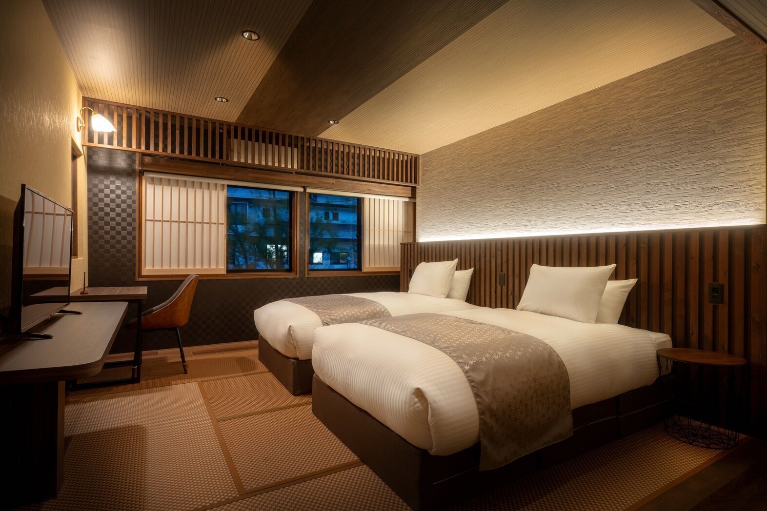 Une chambre d’hôtel moderne, dotée d’un grand lit, d’un bureau et offrant une vue sur le paysage urbain par les fenêtres.