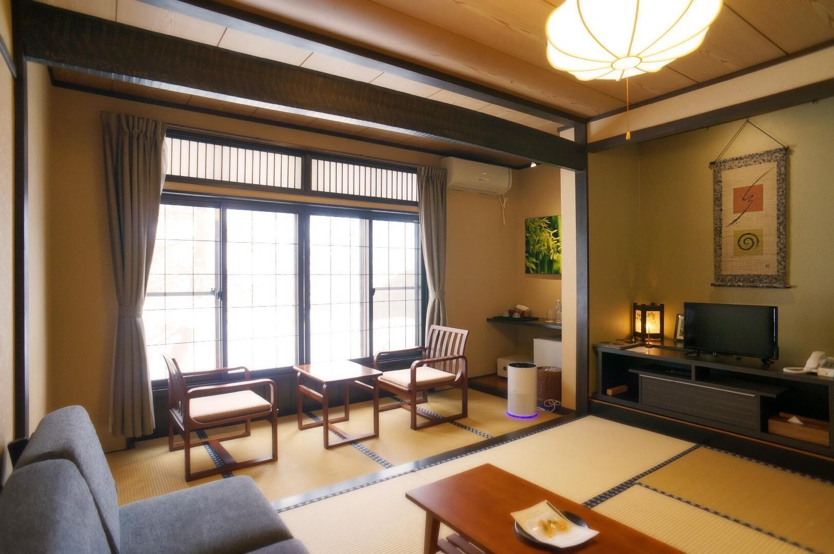 A traditional Japanese-style room with tatami flooring, a sofa, a TV, and a fireplace.