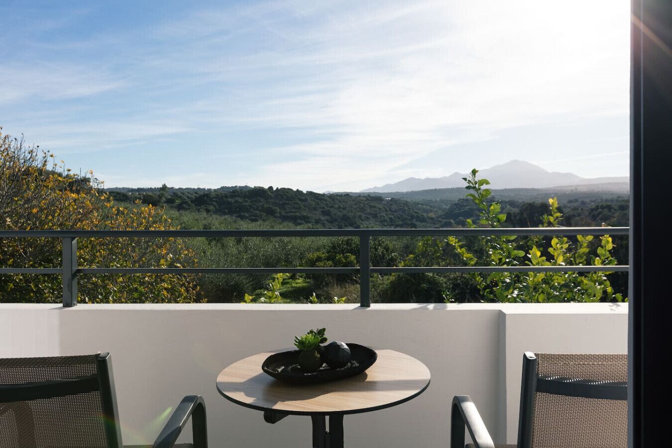 Un balcó amb taula i cadires, amb vista a un paisatge de muntanyes.