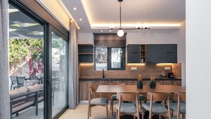 Une cuisine moderne avec un coin repas, de grandes fenêtres et une vue sur la verdure.