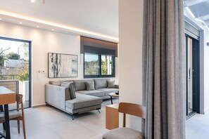 Un salon moderne avec un canapé d’angle gris, une table basse et un coin repas comprenant une table et des chaises en bois.