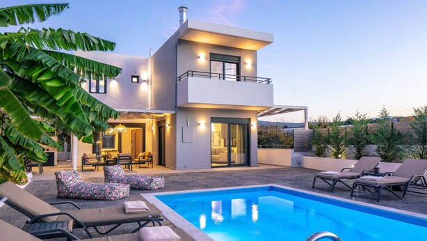 Une maison moderne à deux étages, dotée d’une piscine, d’un espace extérieur aménagé et d’un intérieur bien éclairé.