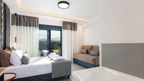 Une chambre d’hôtel moderne dotée d’un grand lit, d’un canapé, d’une salle de bain séparée et offrant une vue sur les montagnes.