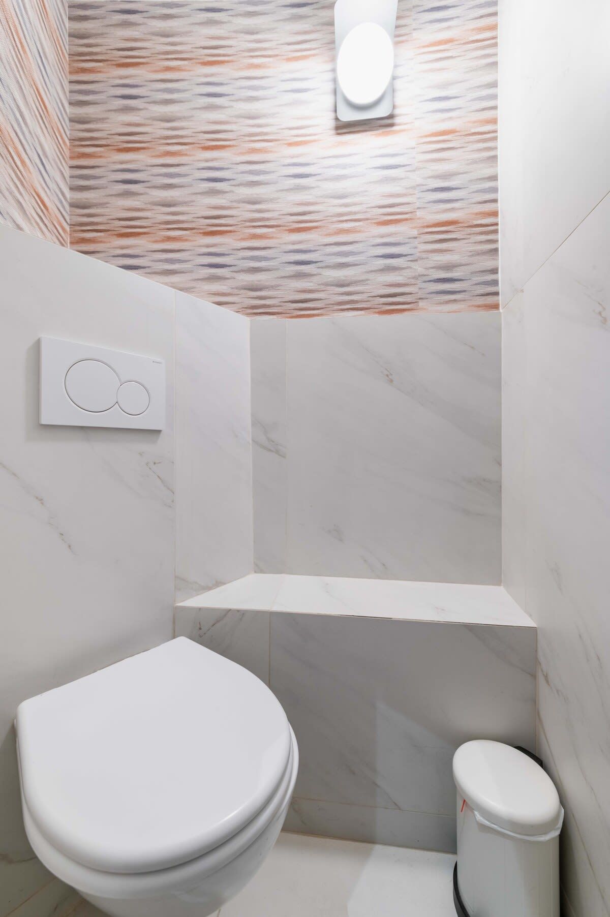 A modern bathroom with a marble floor, a white toilet, and a wall-mounted toilet paper holder.