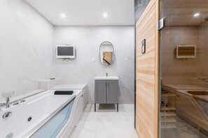 A modern bathroom with a large bathtub, a vanity with a mirror, and a shower area. - Spa prive a domicile - Sauna elegance a Paris 17 (Paris)