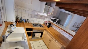 A kitchen with a double sink, stove, microwave, and cabinets. - Charming chalet-style accommodation, 12 minutes from the town center (Schiltigheim)
