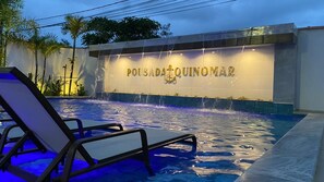 Una piscina con fuente y sillas de descanso.