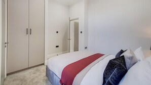A bedroom with a bed, a wardrobe, and a door leading to another room. - Lovely 1-bed Apartment in London With Courtyard (London)